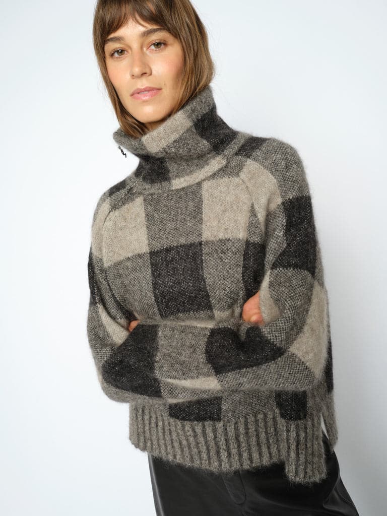 El Jersey Check es una prenda cálida y versátil, perfecta para completar tus looks durante los días más fríos. Su diseño de cuadros en tonos negro y gris aporta un aire atemporal y fácil de combinar. Además, está confeccionado principalmente con mohair, un material agradable que aporta calidez y una textura especial.