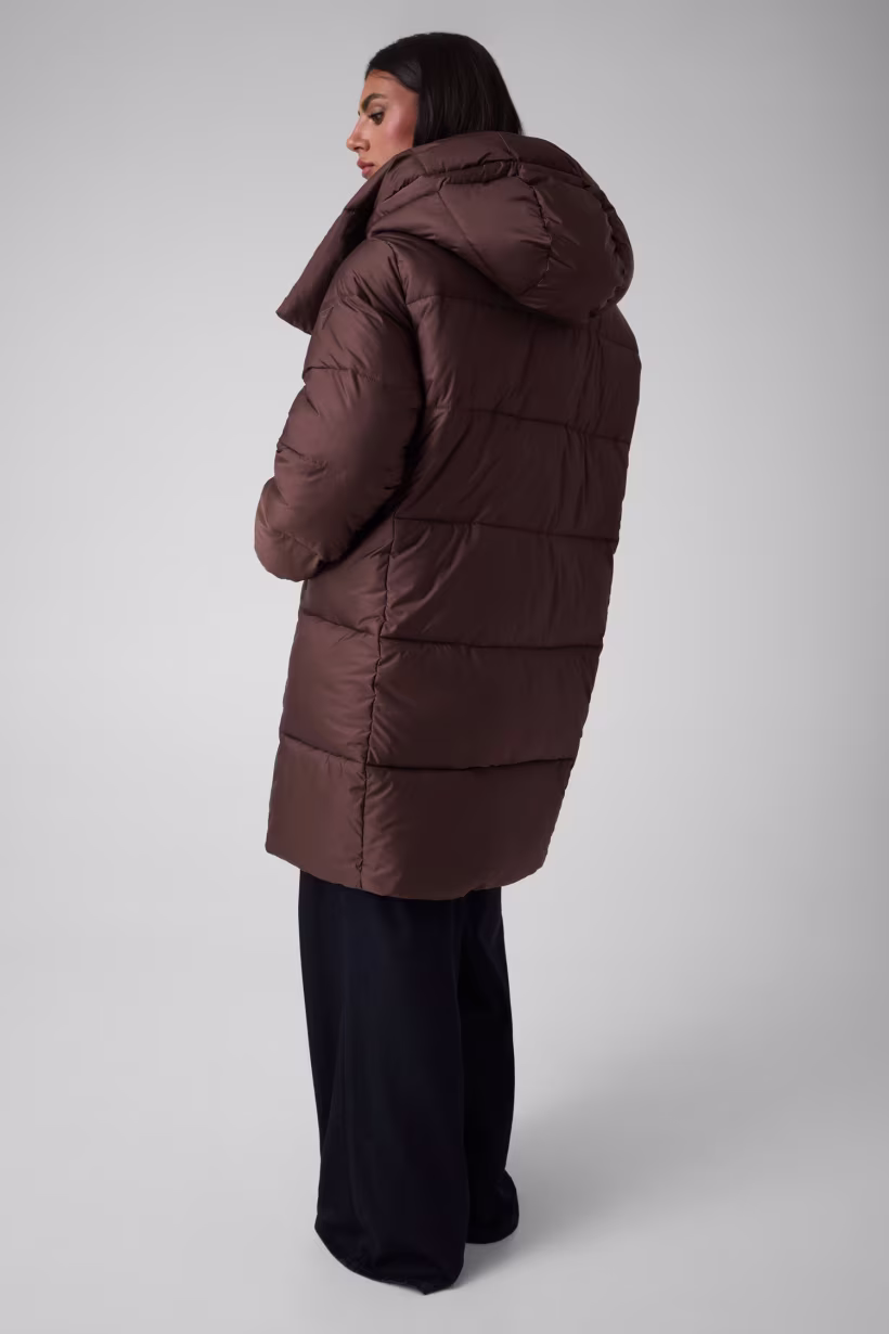 El Plumífero Slow destaca por su diseño moderno y desenfadado, una propuesta de abrigo que combina una silueta actual con detalles originales. Su color marrón aporta una estética cálida y elegante, mientras que su largo hasta las rodillas proporciona una cobertura amplia para los días más fríos. Además, su diseño acolchado refuerza su carácter invernal y aporta volumen a la prenda.